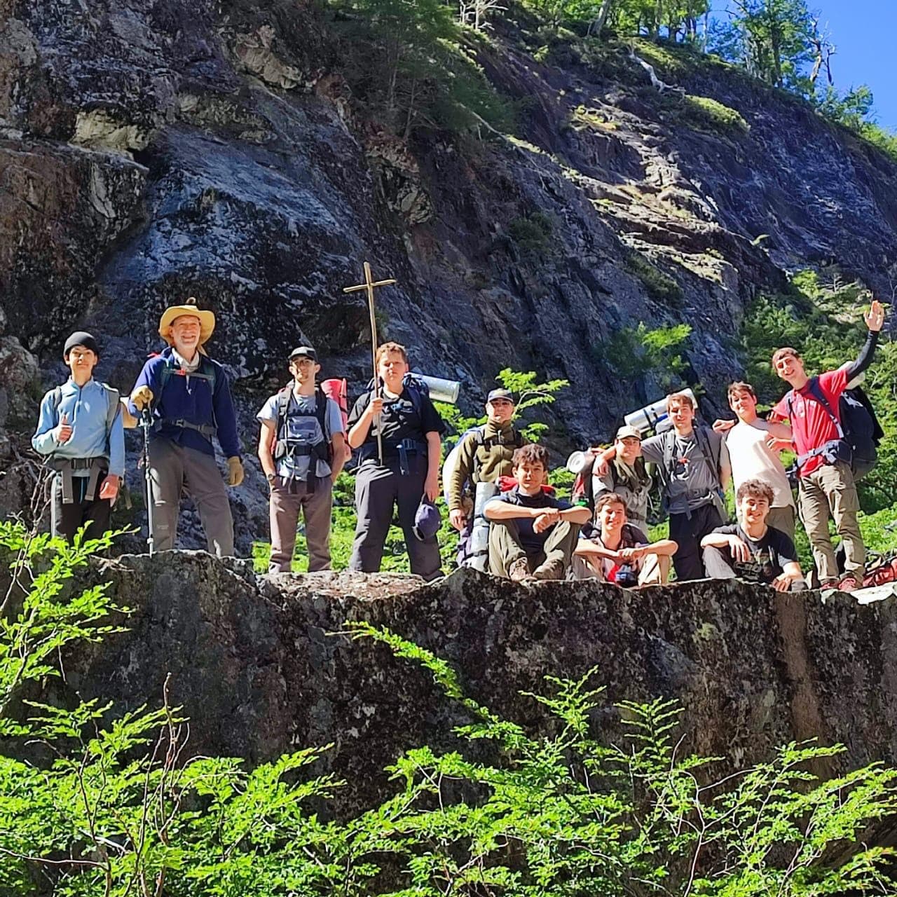 El grupo posando sobre una gran roca al pie de un farallón, uno de ellos con una cruz de madera
