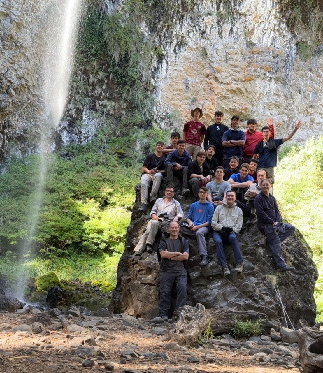 Todo el campamento sentado sobre una roca al pie de una cascada